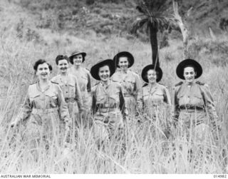 1943-06-10. NEW GUINEA. AT AN AUSTRALIAN GENERAL HOSPITAL IN NEW GUINEA. SISTERS OFF DUTY HIKING THROUGH THICK KUNAI GRASS. LEFT TO RIGHT SISTERS E MCELNEA OF INGHAM, NORTH. QUEENSLAND, M. CONROY ..
