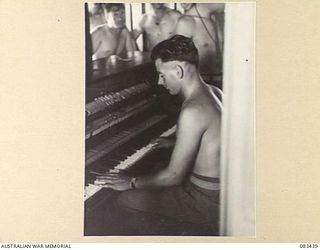 AT SEA, NEW GUINEA AREA, 1944-11-12. SIGNALLER K.J. CALLAHAN, 35 HEAVY WIRELESS SECTION, PLAYING THE PIANO IN THE SHIP'S RECREATIONAL HALL ABOARD USS MEXICO