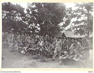 RABAUL, NEW BRITAIN. 1945-11-06. TROOPS OF HEADQUARTERS 11 DIVISION LISTENING TO JIM CARROL'S DESCRIPTION OF THE RUNNING OF THE MELBOURNE CUP