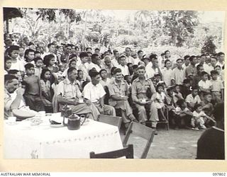RATONGOR, NEW BRITAIN. 1945-10-10. MAJOR GENERAL B.M. MORRIS, COMMANDER, AUSTRALIAN NEW GUINEA ADMINISTRATIVE UNIT, AND MR B. AKUN, HEAD OF THE CHINESE COMMUNITY, SITTING AT A TABLE LISTENING TO ..