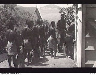 HANUABADA, NEW GUINEA. 1943-10-23. NATIVE MEMBERS OF THE ROYAL PAPUAN CONSTABULARY RECEIVING THEIR RATIONS FROM AN AUSTRALIAN NCO