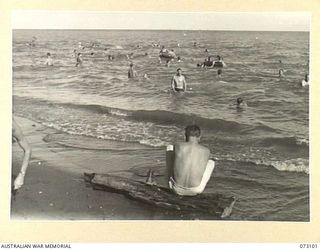 MALAHANG BEACH, NEW GUINEA. 1944-05-14. AUSTRALIAN AND ALLIED TROOPS RELAXING AT THE SEA NEAR LAE. SWIMMERS AT THE MID FOREGROUND FLOAT ON OLD MOTOR TYPE TUBES AND AIRCRAFT BELLY TANKS