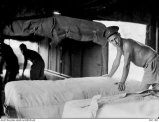 17 MILE, PORT MORESBY AREA, NEW GUINEA. 1943-12-04. TRUCK BEING LOADED WITH FRESHLY LAUNDERED SHEETS AND PILLOW CASES AT THE 9TH AUSTRALIAN DIVISION MOBILE LAUNDRY