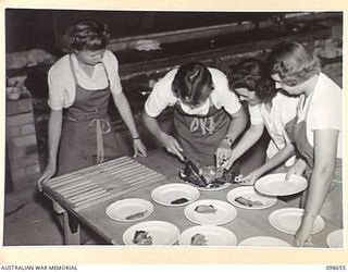 LAE, NEW GUINEA. 1945-11-08. SERGEANT J. CRAWFORD, AUSTRALIAN WOMEN'S ARMY SERVICE INSTRUCTOR WITH SERGEANT D.J. WADE, PRIVATE G. KIRLEY AND SERGEANT B. RANDLE, CARVING THE ROAST AND SERVING ..