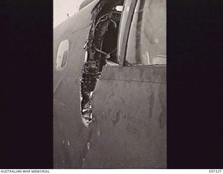 SOPUTA, NEW GUINEA. 1943-09-29. CLOSE UP OF HOLES IN THE MITCHELL BOMBER "PI JOE" FUSELAGE WHICH WAS CAUSED BY PORTION OF THE PROPELLER BREAKING OFF AND PENETRATING THE NAVIGATOR'S COMPARTMENT
