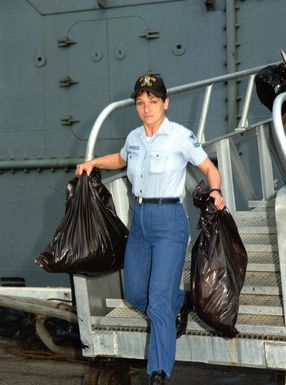 Sailors remove trash from the submarine tender USS HOLLAND (AS-32) in preparation for liberty call following a 45 day period at sea