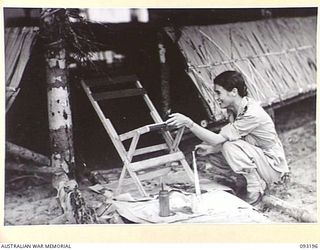 BOUGAINVILLE, 1945-06-18. SISTER G.I. SMITH OF 109 CASUALTY CLEARING STATION, MOTUPENA POINT, PAINTING A CHAIR IN HER SPARE TIME