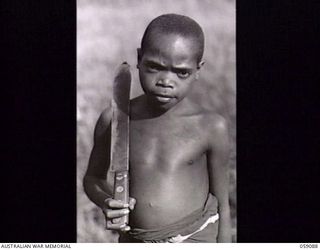 BUKAUA, NEW GUINEA. 1943-10-18. PORTRAIT OF GUTOP WITH MACHETTE ON HIS RIGHT SHOULDER, A VOLUNTEER FOR THE AUSTRALIAN AND NEW GUINEA ADMINISTRATION UNIT LABOUR FORCE, WAS REJECTED BECAUSE OF AGE