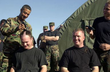 US Air Force (USAF) Captain (CAPT) L.D. Buerger, right and Lieutenant (LT) Ken King, with the 7th Expeditionary Maintenance Group (EMXG), have their heads shaved by CHIEF MASTER Sergeant (CMSGT) Randy Lang and AIRMAN First Class (A1C) Paul Brady at Andersen Air Force Base (AFB), Guam