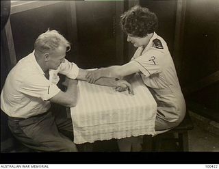 Port Moresby, New Guinea. 1944-05-09. VFX92823 Lieutenant J. Dickson, Pyhsiotherapist, massaging the arm of QX31902 Private Houghton in the Physiotherapy Room at 128th Australian General Hospital