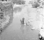 Woman washing child in stream