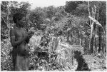 Woman by trench cut into ground by garden