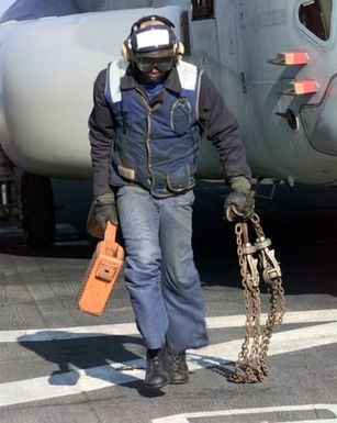 AIRMAN (AN) Rodney Williams of Memphis, Tennessee, removes the tire stops and chains from a MV-22B Osprey's landing gear prior to its launch