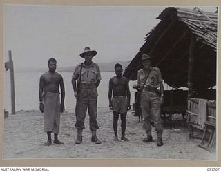 CAPE WOM, WEWAK AREA, NEW GUINEA. 1945-05-06. WARRANT OFFICER 2 H. WALBY (1), AND LIEUTENANT J.A. BIRRELL (2), AUSTRALIAN NEW GUINEA ADMINISTRATIVE UNIT PATROL OFFICERS, WITH NATIVE BOYS. THE MEN ..