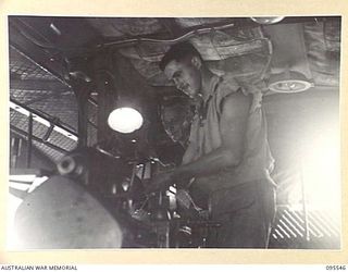 CAPE WOM, WEWAK AREA, NEW GUINEA, 1945-08-24. CRAFTSMAN R. GOODE OPERATING A JAPANESE LATHE WHICH WAS CAPTURED DURING THE BATTLE FOR WEWAK. WARRANT OFFICER 1 WILLIAMS LOOKS ON. THE MEN ARE MEMBERS ..