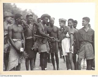 TINIAN, BOUGAINVILLE, 1945-07-18. NETHERLANDS EAST INDIES ARMY PERSONNEL, FORMERLY PRISONERS OF WAR OF THE JAPANESE, FAREWELLING NATIVES OF THE ALLIED INTELLIGENCE BUREAU, WITH WHOM THEY HAD LIVED ..