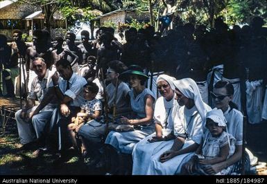 Group of officials and nuns seated with group of Papua New Guineans standing behind