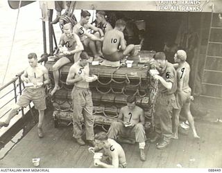 AT SEA. 1945-03-31. HEADQUARTERS 26 INFANTRY BRIGADE TROOPS HAVING BREAKFAST ON THE TOP DECK ABOARD THE VAN HEUTSZ DURING THE MOVEMENT OF HEADQUARTERS 26 INFANTRY BRIGADE PERSONNEL TO MILNE BAY. ..
