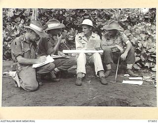 SARANG HARBOUR, NEW GUINEA. 1944-06-01. OFFICERS OF THE 37/52ND INFANTRY BATTALION CHECKING THE ALLOCATION OF BARGES DURING THEIR PREPARATIONS FOR THE BEACH LANDING ON KARKAR ISLAND. IDENTIFIED ..