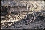 House that has burned down in a fire, Tukwaukwa village on Kiriwina, man piles debris