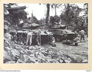 TOROKINA AREA, BOUGAINVILLE. 1945-07-22. PERSONNEL CLEARING MUD OFF THE TRACKS OF THE M24 GENERAL CHAFFEE LIGHT TANKS WHICH ARE GOING THROUGH TESTS FOR THE WAR OFFICE