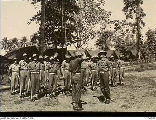 Lae, New Guinea. 1944-07-27. Sergeant H. H. Facey (10) handing over the morning parade of 22 Platoon, F Company, 2/1st Guard Regiment, to the unit Commanding Officer, Lieutenant E. Browning (9). ..