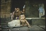 Man and baby on veranda, another child in house