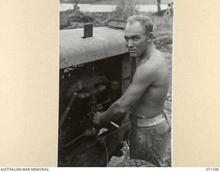 EVAPIA RIVER, NEW GUINEA, 1944-03-15. NX33702 SAPPER A.C. HOLMES OF THE 2/4TH FIELD COMPANY, ROYAL AUSTRALIAN ENGINEERS TENDING AN AIR COMPRESSOR USED IN CONSTRUCTION OF A SUSPENSION BRIDGE ACROSS ..