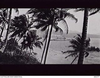 SAMARAI, NEW GUINEA. 1932-09-21. STARBOARD SIDE VIEW OF THE HEAVY CRUISER HMAS AUSTRALIA (II) SEEN FROM THE BEACH. AN AIRCRAFT HANDLING CRANE HAS NOW BEEN FITTED BUT THERE IS STILL NO CATAPULT. ..