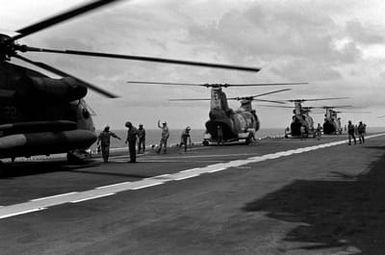 A CH-53D Sea Stallion helicopter attached to Marine Medium Helicopter Squadron 261 (HMM-261), left, and three CH-46E Sea Knight helicopters of HMM-261 start up their engines on the flight deck of the amphibious assault ship USS SAIPAN (LHA 2) during a rehearsal for Operation Sharp Edge. The SAIPAN is on station off the coast of Liberia