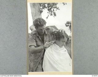 1943-06-10. NEW GUINEA. AT AN AUSTRALIAN GENERAL HOSPITAL IN NEW GUINEA. PRIVATE G.C. MCLACHLAN OF PLAYFIELD, BRISBANE CUTS THE HAIR OF SISTER N. O'TOOLE, PERTH. (NEGATIVE BY N. BROWN)