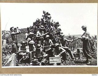 KAKAKOG, NEW GUINEA. 1943-11-07. TROOPS OF THE 12TH BATTERY, 2/4TH AUSTRALIAN LIGHT ANTI-AIRCRAFT REGIMENT RECEIVING AND READING THEIR MAIL NEAR ONE OF THEIR CAMOUFLAGED 40MM BOFORS GUNS. SHOWN ..