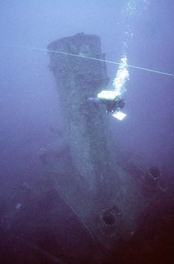 A Navy diver from Moible Diving Salvage Unit One tracks a survey line past the stack on the sunken World War II Japanese merchant ship KIZUGAWA MARU during Project Sea Mark, a four year undersea survey and mapping study of naval historic sites. The study is being conducted in conjunction with the U.S. Park Service's Submerged Cultrual Resource Unit