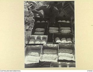 HANSA BAY, NEW GUINEA. 1944-07-29. NX126327 CORPORAL H.L. BERRY, BAKER OF THE 30TH INFANTRY BATTALION FIELD BAKERY PROVING BREAD BEFORE PLACING IT IN THE OVENS