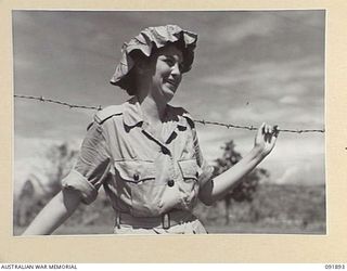 LAE, NEW GUINEA, 1945-05-18. SIGNALWOMAN M. MONGER, AUSTRALIAN WOMEN'S ARMY SERVICE BARRACKS, WEARING A GIANT VINE LEAF AS A CHANGE FROM HER DIGGER HAT WHILE TAKING PART IN A TOUR OF THE AREA ..
