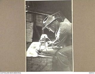 NEW GUINEA. 1943-11-28. VX133 BRIGADIER S. H. W. C. PORTER, DSO, ED, COMMANDING 24TH AUSTRALIAN INFANTRY BRIGADE, STUDYING AERIAL PHOTOGRAPHS THROUGH A STEREOSCOPE