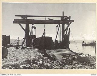 JACQUINOT BAY, NEW BRITAIN. 1945-06-09. THE BARGE REPAIR YARDS AND HOIST FOR 53 PORT CRAFT COMPANY, ROYAL AUSTRALIAN ENGINEERS, AT 5 BASE SUB-AREA. THE BARGE ANCHORAGE IS PROTECTED BY THE REEF ..