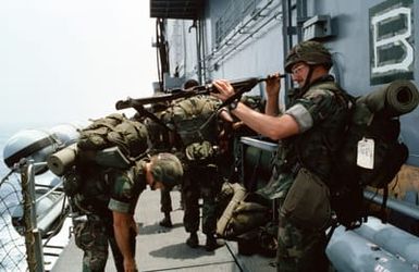 Marines of the 22nd Marine Expeditionary Unit (22nd MEU) check their equipment aboard the amphibious assault ship USS SAIPAN (LHA 2) while waiting to board a helicopter during Operation Sharp Edge. The Marines will be flown to the U.S. Embassy in Monrovia, Liberia, to augment security and evacuate U.S. and foreign nationals from the fighting between government and rebel forces