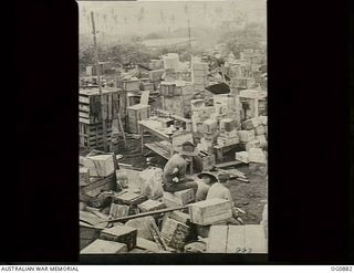KIRIWINA, TROBRIAND ISLANDS, PAPUA. 1943-11-27. THREE AIRMEN SIT AMONGST SQUADRON STORES UNLOADED FROM SHIP AND READY TO BE SORTED OUT TO VARIOUS SECTIONS FOLLOWING THE MOVE OF NOS. 22 AND 30 ..