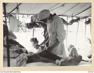 WEWAK AREA, NEW GUINEA. 1945-06-03. LIEUTENANT C. LEAHY (1) AND LIEUTENANT K.J. MURCH (2), AUSTRALIAN ARMY NURSING SERVICE SISTERS AT 104 CASUALTY CLEARING STATION PREPARING A BLOOD TRANSFUSION