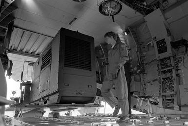 The loadmaster of a C-141B Starlifter aircraft guides a portable electric generator into the cargo hold of the aircraft. The generator is being airlifted to Kauai to provide power to areas left without electricity by Hurricane Iwa