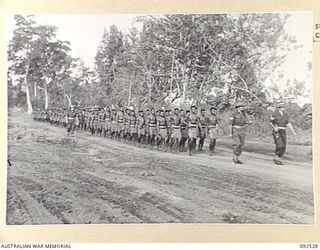 BOUGAINVILLE. 1945-05-23. PERSONNEL OF A COMPANY, PAPUAN INFANTRY BATTALION, MARCHING FROM FREDDIE BEACH, SORAKEN, TO THE PARADE GROUND, FOR AN INSPECTION BY BRIGADIER J.R. STEVENSON, COMMANDER 11 ..