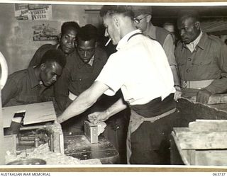 ALEXANDRIA, NSW. 1944-01-24. AUSTRALIAN AND NEW GUINEA ADMINISTRATION UNIT NATIVES WATCHING THE MACHINING OPERATIONS OF A WOODEN COMPONENT FOR A PLYWOOD MOTOR DORY AT SLAZENGER'S FACTORY