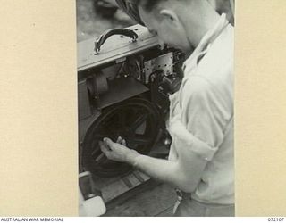 LAKONA, NEW GUINEA. 1944-04-05. NX174273 SERGEANT G.A. PRESTON, ARMY AMENITIES SERVICE, THREADING A FILM THROUGH A 35MM CINE PROJECTOR AT HEADQUARTERS 8TH INFANTRY BRIGADE IN PREPARATION FOR A ..