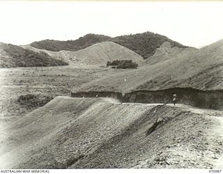 WAU - LAE ROAD, NEW GUINEA, 1944-03-10. ENTERING THE MARKHAM VALLEY, ABOUT 78.5 MILES FROM WAU. FOR TWO TO THREE MILES UNTIL THE ROAD ENTERS JUNGLE THE VIEW IS REMARKABLE, WITH VISIBILITY EXTENDING ..