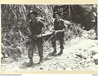 FARIA VALLEY, NEW GUINEA, 1944-02-09. VX59179 GUNNER W.H.D. KERR (1) WITH N346225 GUNNER D.B. MAY (2), MEMBERS OF THE 11TH FIELD BATTERY, 4TH FIELD REGIMENT, CARRYING A BATTERY FOR THE FORWARD ..