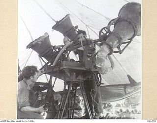 HANSA BAY, NEW GUINEA. 1944-07-10. MEMBERS OF THE 5TH DIVISION SALVAGE GROUP EXAMINE A JAPANESE SOUND DETECTOR AND PLOTTING BOARD