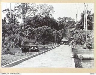 BULUS RIVER, NEW BRITAIN, 1945-08-07. BRIDGE OVER THE BULUS RIVER. A GRAVEL TRUCK OF 55 FIELD PARK COMPANY, ROYAL AUSTRALIAN ENGINEERS, SHOWN CROSSING THE BRIDGE WHILE CA5R WASHING IS GOING ON IN ..