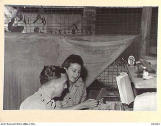 LAE, NEW GUINEA, 1945-05-21. CORPORAL G.S. LITTLEWOOD (1), AND PRIVATE R. BENSLEY AUSTRALIAN WOMEN'S ARMY SERVICE (2), CHECKING STOCK RECORD CARDS AT THE AUSTRALIAN ARMY CANTEENS SERVICE, CANTEEN ..