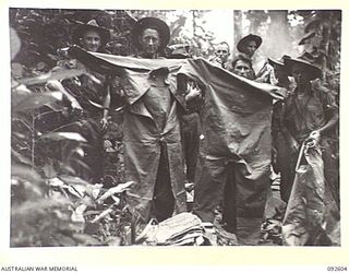 WEWAK AREA, NEW GUINEA, 1945-05-24. PTE R.J. BUCHANAN (1) AND PTE J. DUGGAN (2), 2/8 INFANTRY BATTALION, HOLDING OVERALLS FOUND AT A JAPANESE Q STORE NEAR BORAM. THE OVERALLS WERE INVALUABLE TO OUR ..